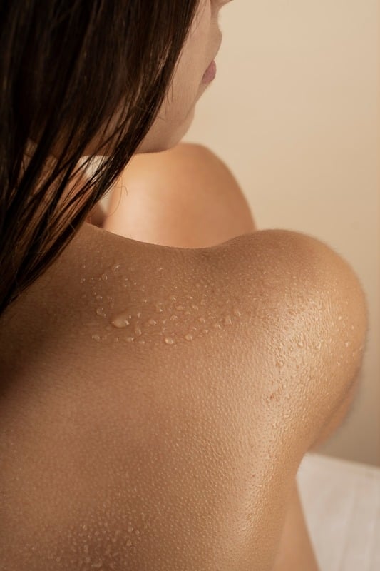 Dettaglio di una schiena femminile con gocce d'acqua